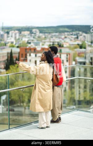 Modische afroamerikanische Paare, die über einen Panoramablick auf die Stadt sprechen. Stockfoto