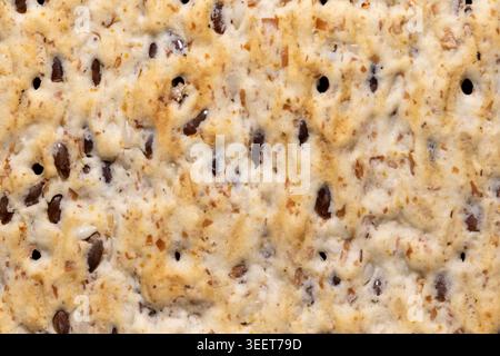 Detaillierte Makrotextur eines gesunden Mehrkorncrackers mit Leinsamen. Draufsicht auf knusprige Bio-Knetbrotoberfläche. Ballaststoffe und gesunde Snacks Stockfoto