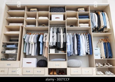 Kleiderschrank mit verschiedenen stilvollen Kleidungsstücken, Accessoires, Schuhen und Haushaltsgegenständen im Innenbereich, geringer Blickwinkel Stockfoto