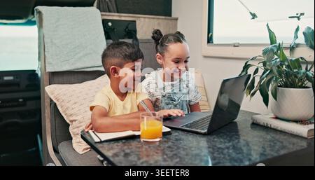 Happy, Laptop und Kinder im Wohnmobil für Online-Videos, Filme und Unterhaltung auf dem Roadtrip. Familie, Geschwister und Kinder am Computer für das Internet Stockfoto