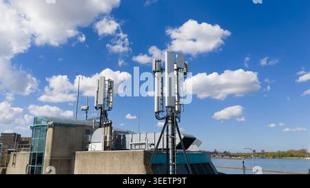 Luftaufnahme von Telekommunikationsantennen und Mobilfunktürmen auf dem Dach des Gebäudes unter blauem Himmel mit weißen Wolken Amsterdam, Nordholland, Nethe Stockfoto