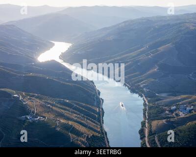 Aus der Vogelperspektive eines touristischen Kreuzfahrtschiffes, das durch das Douro-Tal zwischen terrassenförmig angelegten Weinbergen in Portugal fährt. Stockfoto