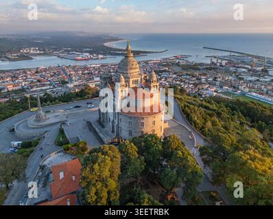 Drohnenaufnahme der Basilika Santa Luzia zur goldenen Stunde mit der Stadt Viana do Castelo und dem Atlantischen Ozean, Portugal. Stockfoto