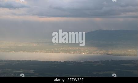 Aus der Vogelperspektive von Le Colomby de Gex mit Blick auf den Jura und den Genfer See unter einem dramatischen bewölkten Himmel mit Sonnenstrahlen in Echenevex, Auvergne-Rhone Stockfoto