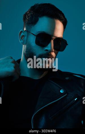 Serious, Mode und Mann mit Sonnenbrille im Studio für Rockstar-Chic, trendiges Selbstvertrauen und Style. Lederjacke, Person und Schatten auf dunklem Hintergrund Stockfoto