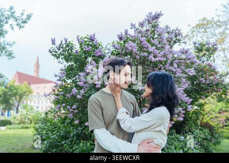 Glückliches multikulturelles Paar, das Hände hält und im blühenden Frühlingspark in Breslau in Europa spaziert Stockfoto