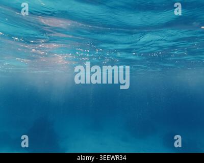Wunderschöner Blick unter Wasser mit Sonnenstrahlen durchdringen klares blaues Meer und Sandboden im Roten Meer. Stockfoto
