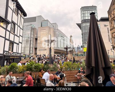 Geschäftige Fußgängerzone in der Nähe von Selfridges und Harvey Nichols mit Abendessen im Freien. Stockfoto