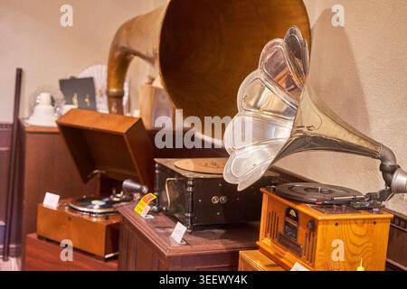 Eine Sammlung von Vintage-Grammophonen und Phonographen, die in einer Museumseinrichtung oder einem Antiquitätenladen ausgestellt sind. Das Bild zeigt mehrere antike Hörner Stockfoto