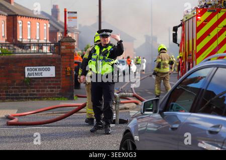 Ein Polizist, der den Verkehr von einem Brand im ehemaligen Festival Foods Lagerhaus in Osmondthorpe, Leeds, West Yorkshire, Großbritannien ablenkt Stockfoto