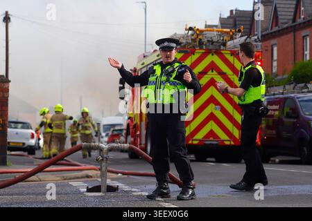 Ein Polizist, der den Verkehr von einem Brand im ehemaligen Festival Foods Lagerhaus in Osmondthorpe, Leeds, West Yorkshire, Großbritannien ablenkt Stockfoto