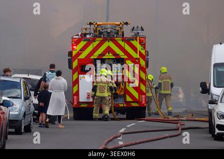 Feuerwehrmannschaft und Mitglieder der Öffentlichkeit am Ort eines Brandes im ehemaligen Festival Foods Warehouse in Osmandthorpe, Leeds, West Yorkshire, Großbritannien Stockfoto