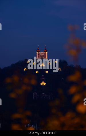 Historischer Calvary Komplex, der in der Abenddämmerung auf einem Hügel glänzt und durch Herbstlaub blickt Stockfoto