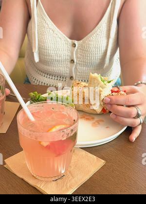 Hände der Frau im Sommer Top essen Wrap Lunch am Café Tisch mit Limonade, Salat, Teller. Konzept der Mittagspause, zwangloses Essen, ehrlicher Lebensstil, Ref Stockfoto