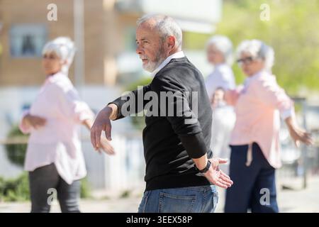 Reifer Mann, der im Freien Armschwingübungen macht Stockfoto