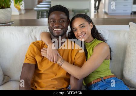 Afroamerikanisches Paar sitzt dicht auf einem leichten Stoffsofa, Frau wickelt Arm, Armbänder sichtbar Stockfoto