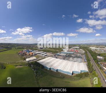 Luftaufnahme großer Industrielager und Geschäftsgebäude, umgeben von grünen Feldern unter blauem Himmel mit Wolken in Grangemouth, Schottland, Stockfoto