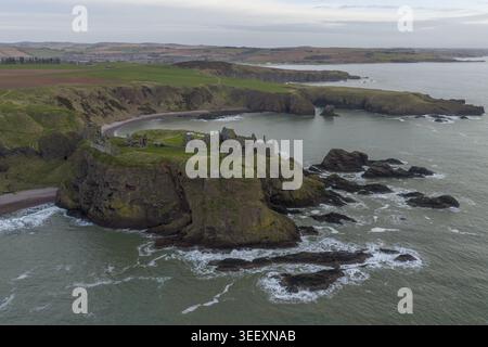 Blick aus der Vogelperspektive auf die mittelalterlichen Ruinen von Dunnottar Castle auf einer dramatischen felsigen Landzunge, umgeben von der Nordsee und grünen Klippen in Stonehaven, Stockfoto