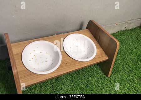 Zwei leere weiße Schüsseln auf einem hölzernen Tablett, Essensbrösel verstreut am Boden der Schüsseln Stockfoto