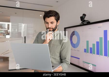 Fokussierter Analyst, der Daten auf modernen Notebooks überprüft Stockfoto