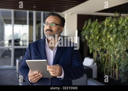 Durchdachter Geschäftsmann, der Daten auf einem digitalen Tablet im Büro analysiert Stockfoto