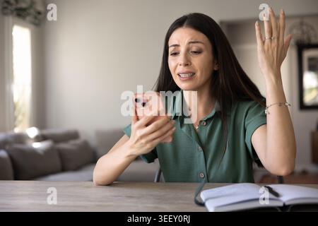 Verärgerte Frau, die auf stressige Telefonnachrichten reagiert Stockfoto