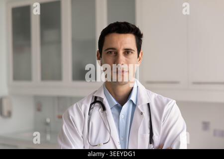 Selbstbewusster Arzt, der in die Kamera schaut, in der Klinik steht Stockfoto