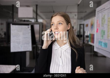 Eine junge Frau, die im Büro telefoniert Stockfoto