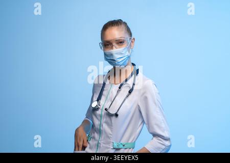 Junge Ärztin oder Krankenschwester Facharzt mit chirurgischer Maske und Schutzbrille, die das medizinische Personal an vorderster Front repräsentiert Stockfoto