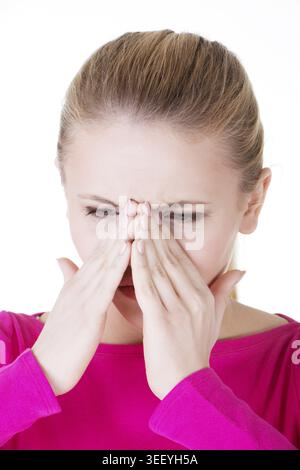 Die junge kaukassische Frau hat einen Sinusdruck und berührt ihre Nase. Isoliert auf weiß Stockfoto