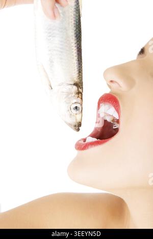 Schöne junge Frau, die rohen Fisch isst, isoliert auf weiß Stockfoto