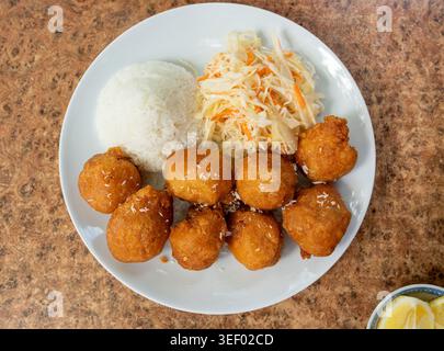 Gebratene Hähnchenbällchen mit Reis und frischem Kohlsalat in der Nähe. Frittierte Teigbällchen in einem Straßenrestaurant auf verschwommenem Hintergrund von oben Stockfoto