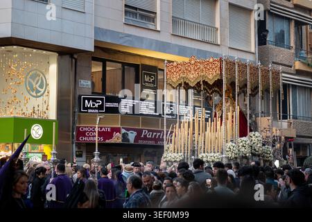 Almeria, Spanien - 30. März 2026: Ein Prozessionswagen der Karwoche mit einem heiligen Bild der Jungfrau Maria bewegt sich durch eine überfüllte Straße, umgeben von der Stadt Stockfoto