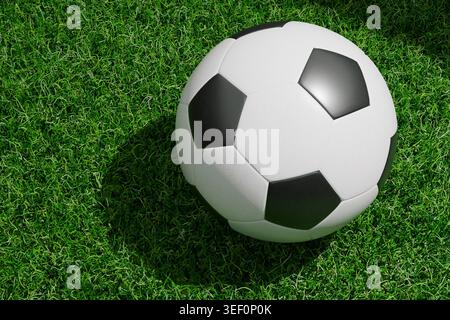 Klassischer schwarz-weißer Fußball, der auf einem grünen Rasenfeld mit Sonnenlicht liegt. Perfekt für Sport, Fußballmeisterschaft und Outdoor-Aktivitäten Stockfoto