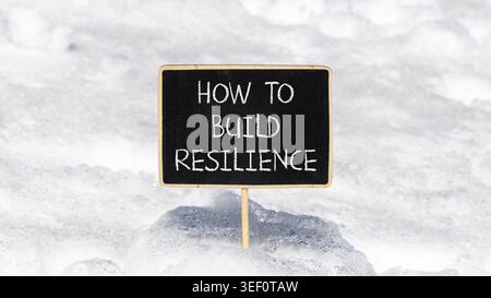 So erstellen Sie ein Resilienzsymbol. Konzeptworte wie man Widerstandsfähigkeit auf schönen Tafeln schafft. Schöner weißer Schnee Hintergrund. Business wie man baut Stockfoto