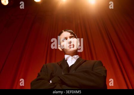 Eine junge Künstlerin fesselt das Publikum mit ihrer kraftvollen Präsenz in einem lebendigen Theater. Stockfoto