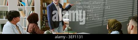 Studenten mit Migrationshintergrund, die im Unterricht mit dem Lehrer Finanzbedingungen lernen Stockfoto