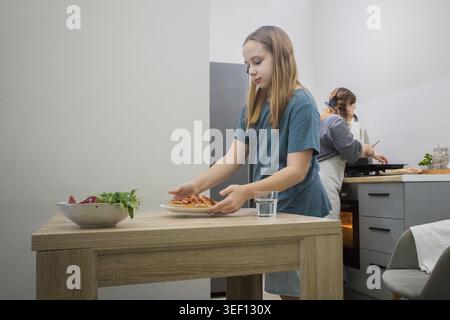 Italienische Pizza. Familienkost in der Hausküche. Mutter und Tochter bereiten zu Hause Essen vor Stockfoto