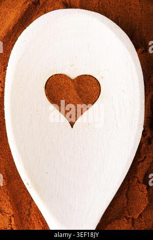 Herzform aus Gewürz auf einem Holzlöffel. Zusammensetzung Stockfoto