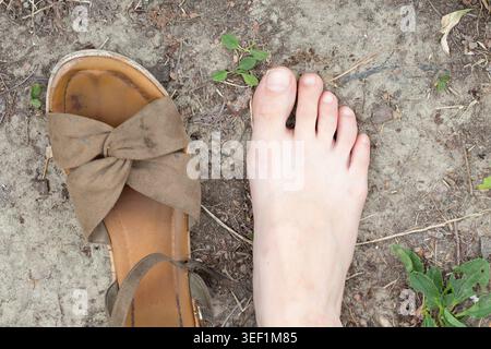 Barfußkontrast mit einer Sandale, die die Wahl zwischen Natur und Schuhen zeigt Stockfoto