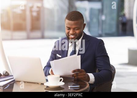 Geschäftsmann am Laptop arbeiten mit Papieren sitzen im Café im Freien Stockfoto