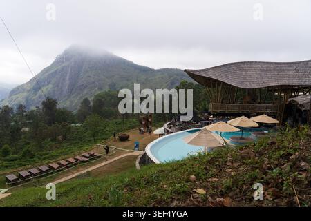 Luxuriöser Außenpool und Bambus Lounge unter einem nebeligen Berggipfel an einem bewölkten Tag in einem tropischen Resort in Ella, Sri Lanka Stockfoto