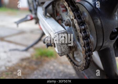 Nahaufnahme von Kette und Kettenrad mit Verschleiß und Schmutz, Schmierspuren und Metallermüdung sichtbar, Spannung Stockfoto