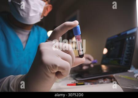 Medizinischer Fachmann in Peelings und Handschuhen, die ein mit Hantivirus gekennzeichnetes Blutprobenröhrchen halten Stockfoto