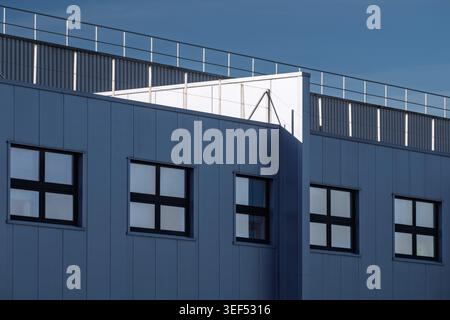 Architektonische Außenansicht eines modernen Industriegebäudes mit schwarz gerahmten quadratischen Fenstern Stockfoto