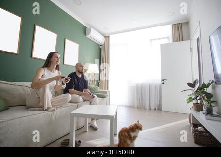 Verheiratetes Paar, das zu Hause Konsolenspiel spielt. Aufregendes Videospiel für aktive Paare Stockfoto