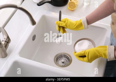 Eine Frau, die Backpulver benutzt, um den Abfluss zu reinigen, zu schließen Stockfoto