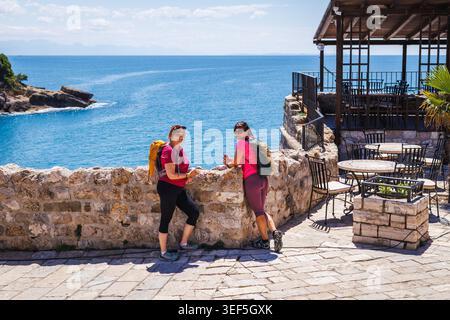 Zwei reife Frauen, die im Sommer aktiv Urlaub in Ulcinj in Montenegro verbringen. Lächelnde weibliche Touristen mit Rucksack Stockfoto