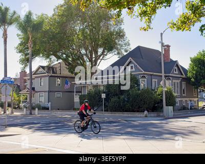 Radfahrer überqueren vor dem Ende des 19. Jahrhunderts viktorianische Häuser im historischen Viertel Ventura, Kalifornien – Oktober 2025 Stockfoto