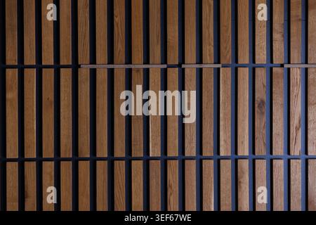 Hintergrundstruktur der dekorativen Wand aus braunen Holzdielen, die vertikal mit dunklen Lücken angeordnet sind. Minimalistisches Innendesign, umweltfreundlich Stockfoto